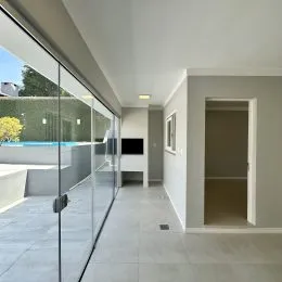 Vista de um espaço interno com porta de vidro que dá acesso a uma área externa com piscina.