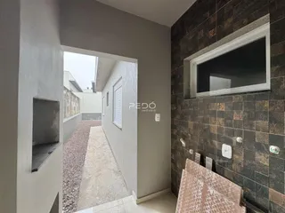 Hall de entrada com parede de tijolos escuros e passagem para o quintal.