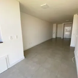 Vista interna de um corredor com paredes brancas e piso claro.
