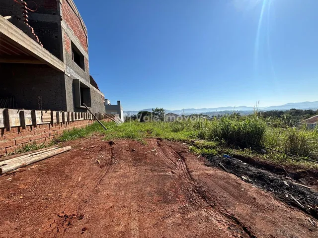 Fachada de um prédio de tijolos com terreno e vegetação ao redor.