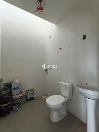 Foto interna de um banheiro com azulejos brancos e itens de pintura no chão.