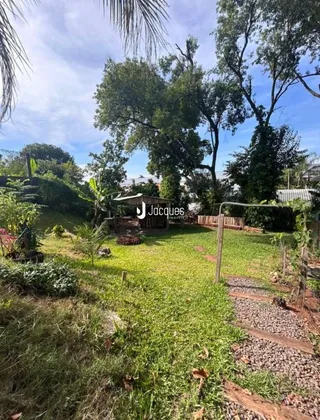 Vista externa de um jardim gramado com árvores ao fundo.