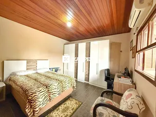 Este é um quarto com cama grande e armários brancos em um ambiente com teto de madeira.