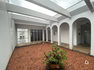Área externa coberta com piso de cascalho avermelhado.