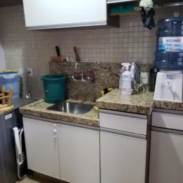 Foto de uma cozinha com bancadas e armários brancos.