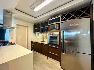 Vista da cozinha moderna com armários de madeira e eletrodomésticos de aço inoxidável.