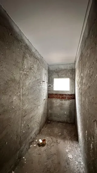 Corredor interno de uma residência com paredes de concreto.