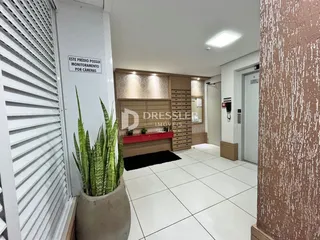 Hall de um apartamento em Lajeado com piso de cerâmica e armários em madeira.