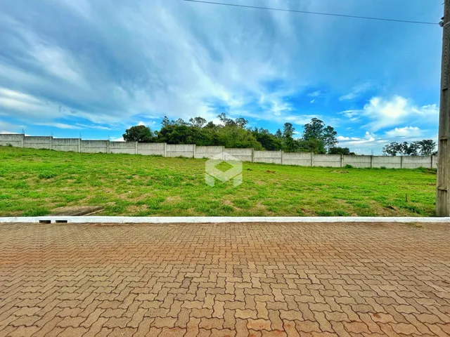 Vista externa de um terreno com cerca branca e vegetação verde.