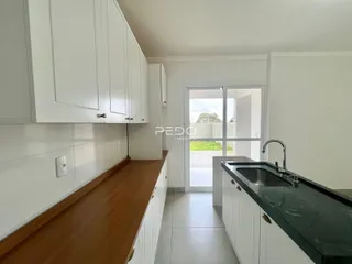 Cozinha com armários brancos e bancada escura.