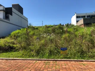 Vista externa de uma propriedade com gramado alto e muros brancos.