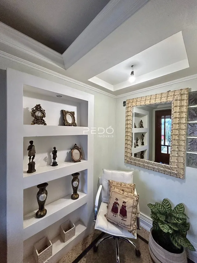 Parede com nichos brancos e um espelho decorativo em um corredor.