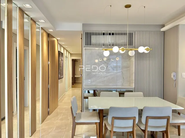 Sala de jantar moderna com mesa de madeira e cadeiras claras.