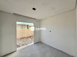 Vista interna de um cômodo com paredes brancas e piso de concreto exposto.