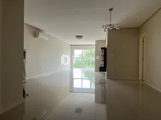 Corredor interno de uma residência com piso claro e grande janela de vidro.