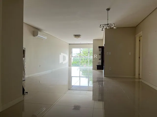 Corredor interno de uma residência com piso claro e grande janela de vidro.