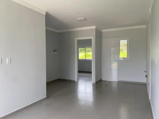 Hall de entrada com paredes brancas e piso claro.