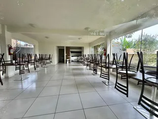 Ambiente interno com mesas e cadeiras alinhadas em um espaço amplo.