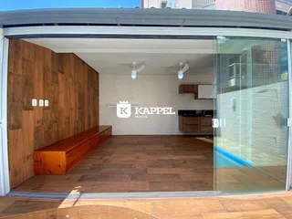 Vista de uma área de estar com piso de madeira e detalhes de cozinha em um imóvel.