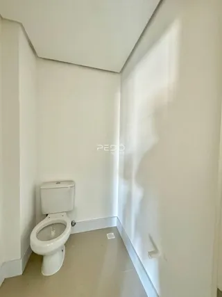 Hall de entrada estreita com vaso sanitário branco e piso claro.