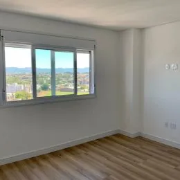 Vista externa através de uma grande janela em um ambiente interno com piso de madeira.