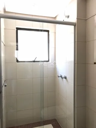 Foto de um banheiro com revestimento cerâmico e box de vidro.