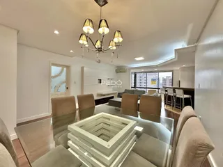 Sala de estar moderna com piso de madeira e grandes janelas.