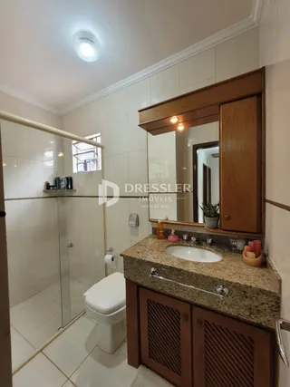 Foto de um banheiro com box de vidro e armário de madeira.