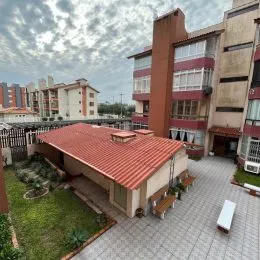 Área externa com piso de ladrilho e gramado.