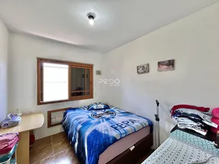 Quarto com cama e janela de madeira em um imóvel no Brasil.