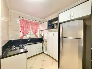 Uma cozinha com armários brancos e bancadas escuras.