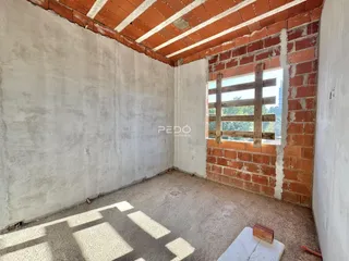 A parede interna da sala apresenta tijolos expostos e teto de madeira.
