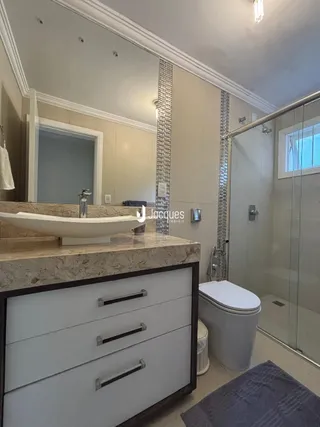 Detalhe de um banheiro com bancada e box de vidro.