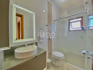 Foto de um banheiro moderno com box de vidro e louças brancas.