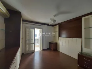 Ambiente interno de uma sala com piso de madeira escura e detalhes em painéis brancos.