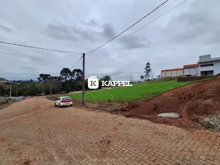Vista externa da propriedade mostrando um campo gramado e uma estrada de terra.