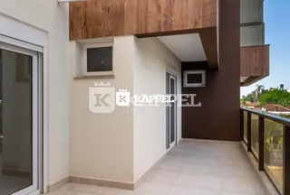 Vista externa da fachada de um imóvel com detalhes em madeira e parede branca.