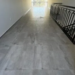 Foto de um corredor longo com piso cinza claro.