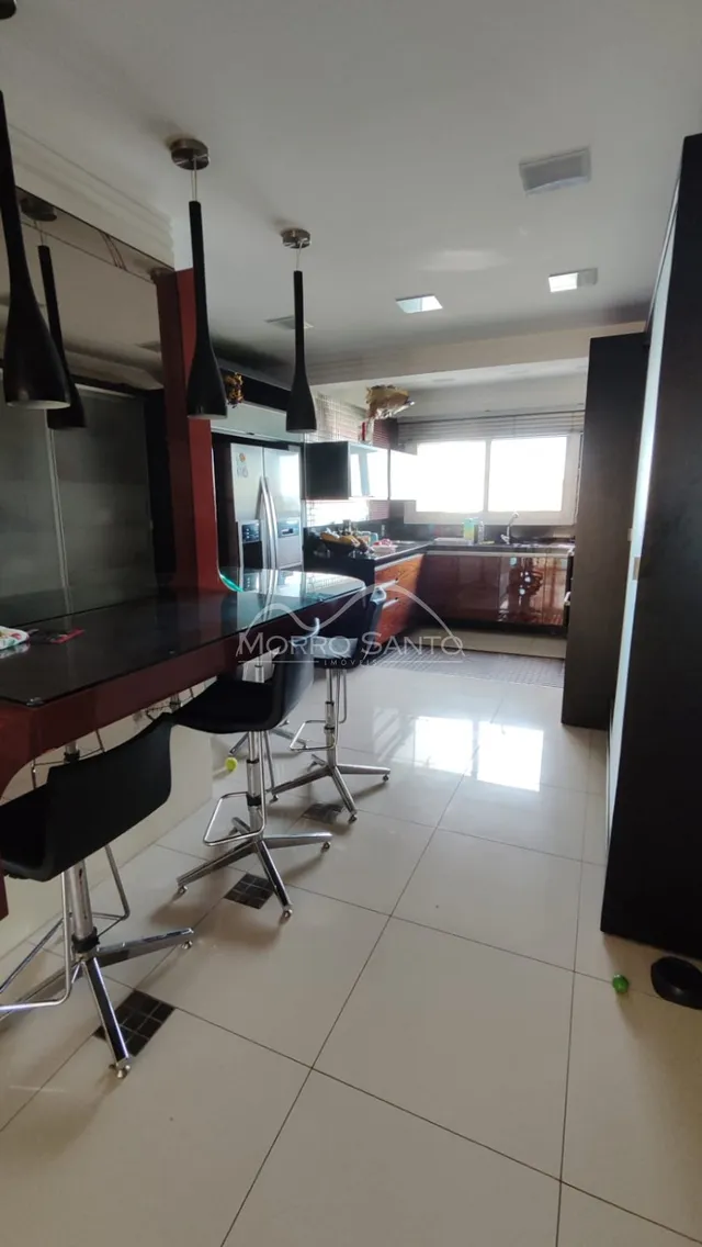 Foto de uma cozinha com ilha e banquetas escuras em um imóvel.
