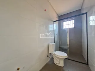 Foto de um banheiro com paredes brancas e divisória de vidro.