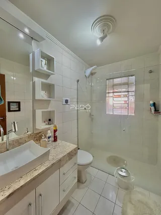 Banheiro com revestimento cerâmico e bancada de mármore claro.