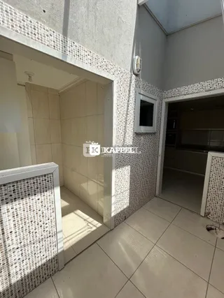 Hall de corredor com piso e paredes revestidos de azulejos claros.