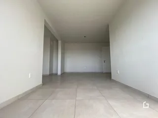 Vista interna de um corredor amplo com paredes brancas e piso claro.