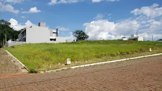 Vista externa de um terreno com vegetação gramada e área pavimentada.