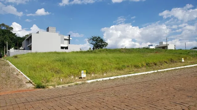 Vista externa de um terreno com vegetação gramada e área pavimentada.