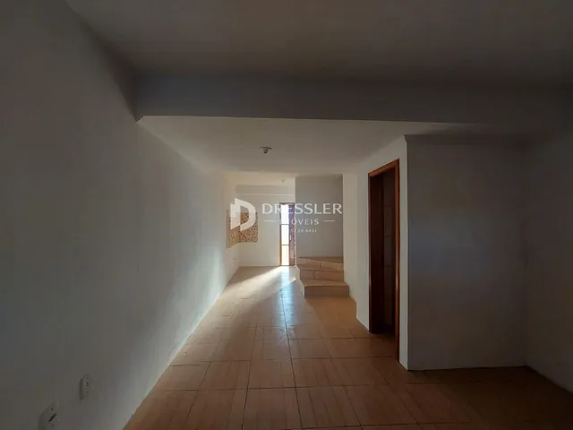 Corredor interno de uma residência com piso de madeira clara.