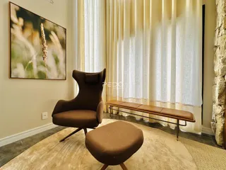 Uma sala de estar com uma poltrona marrom e um tapete claro.