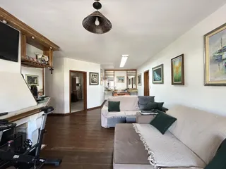 Sala de estar com piso de madeira e sofá claro em um imóvel no Brasil.
