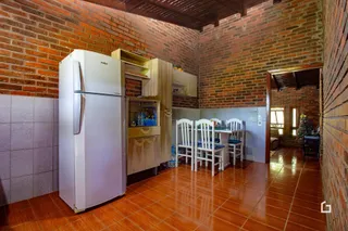 Interior de uma residência com paredes de tijolo aparente e piso de cerâmica.