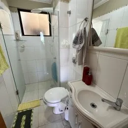 Foto interna de um banheiro com revestimento de azulejos brancos.
